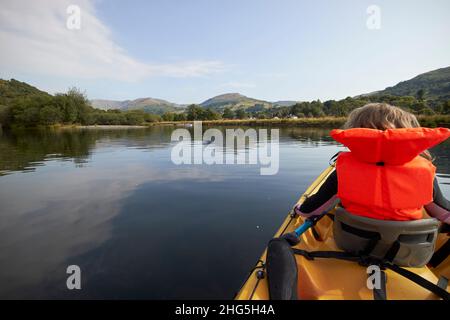 jeune fille de sept ans portant un gilet de sauvetage devant un kayak de deux personnes sur windermere dans le district de lac d'été, cumbria, angleterre, royaume-uni Banque D'Images