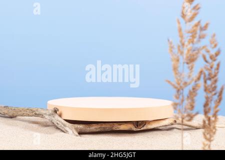 Plate-forme ronde beige podium, branches d'arbre sèches sur sable blanc de plage avec plante tordue sèche en premier plan.Arrière-plan de composition créative minimal pour Banque D'Images