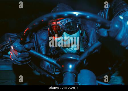 Image rétro de la vieille école d'un pilote de crier fou avec une barbe portant des lunettes vintage et un casque en cuir tout en tenant le volant.Auto Banque D'Images