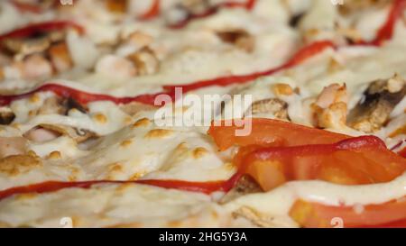 Fond de pizza, fromage gros plan.Cadre.Pizza fraîche en vue macro.Pizza à la mozzarella, jambon, tomates cerises coupées en deux, câpres, épices et basilic frais Banque D'Images