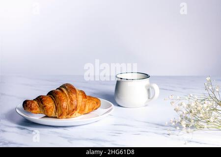 Croissant et tasse de café aux fleurs sèches.Concept du matin romantique. Banque D'Images