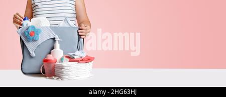 Bannière.Femme emballage sac couches sur rose. Banque D'Images
