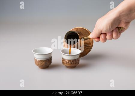 La main d'un homme verse du café noir dans des tasses de café traditionnelles turques.Le concept de minimalisme. Banque D'Images