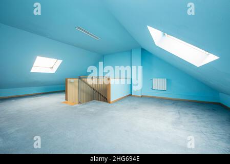 Grenier d'une maison unifamiliale avec moquette bleue au sol et murs peints de la même couleur Banque D'Images