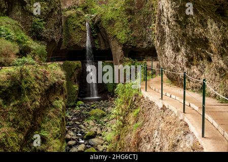 Canal d'eau Levada Nova et sentier de randonnée, passant sous une cascade dans un beau chaudron de roche dans la vallée de Ponta do sol, Madère, Portugal Banque D'Images