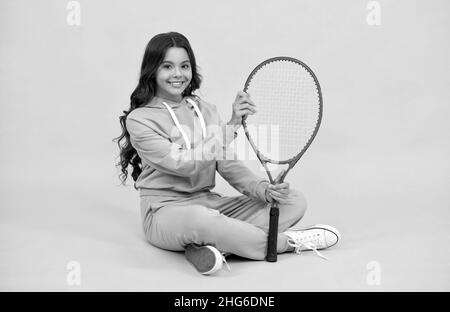 enfant dans les vêtements de sport tenir raquette. enfant avec raquette. jeune fille se détendre après l'entraînement sportif. Banque D'Images