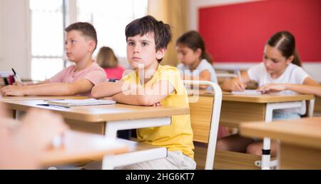 Jeune garçon diligent étudiant avec des camarades de classe à l'école Banque D'Images