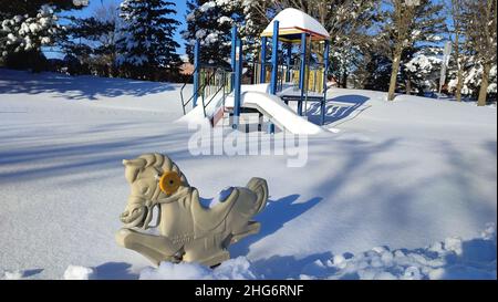 Terrain de jeu en hiver.Zone de loisirs d'hiver pour les enfants.Météo enneigée.L'équipement de l'aire de jeux pour enfants est recouvert de neige avec des arbres en arrière-plan Banque D'Images