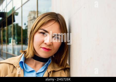 Belle jeune femme penchée contre le mur. Banque D'Images