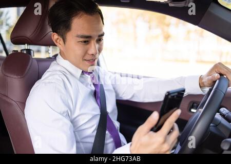 Jeune homme d'affaires regardant un téléphone mobile dans la voiture Banque D'Images