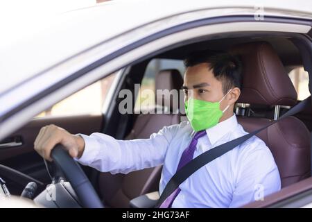 Homme d'affaires portant un masque médical de protection et conduisant dans la voiture pendant l'épidémie de coronavirus Banque D'Images