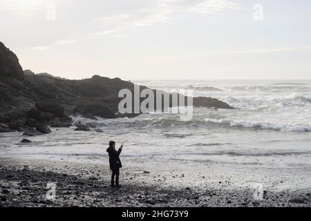 Un visiteur de la plage Short Beach sur la côte de l'Oregon prend des photos avec son téléphone le dimanche 16 janvier 2022, après la levée d'un avis de tsunami. Banque D'Images