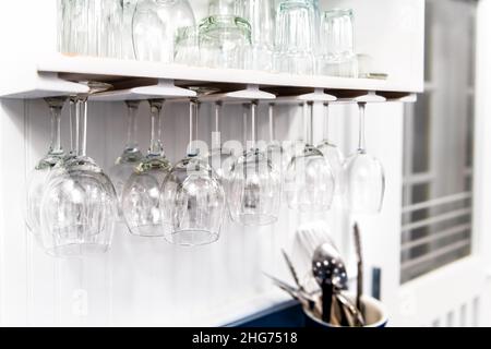 Gros plan de cuisine moderne design intérieur étagère blanche avec à l'envers suspendre verres à vin vides dans la chambre pour ranger des tasses et personne Banque D'Images