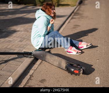 Une femme de race blanche est tombée d'un scooter électrique et a blessé son bras.Souffrant de douleur. Banque D'Images