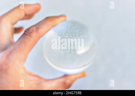 Macro gros plan de l'homme main tenant verre bille de verre de lentille avec réflexion de Bonneville plats de sel paysage comme concept de prédiction Banque D'Images