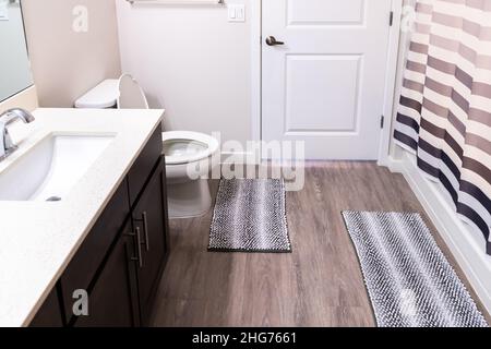 Vide salle de bains intérieur dans nouveau moderne appartement de luxe maison et toilette blanche avec tapis, armoires de porte et douche rideau de bain style minimaliste Banque D'Images