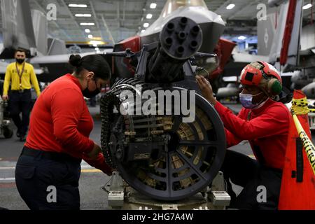OCÉAN PACIFIQUE (janv17, 2022) Aviation Ordnanceman 2nd classe Itzary Romero, à gauche, de Ventura Calif., et Aviation Ordnanceman Airman Joseph Rucker, de St. Louis, affecté aux « Black Aces » de Strike Fighter Squadron (VFA) 41, installent des conduites hydrauliques sur un canon 20mm Gatling dans la baie hangar à bord de l'USS Abraham Lincoln (CVN 72).Abraham Lincoln Strike Group est en cours de déploiement prévu dans la zone d'exploitation de la flotte américaine 7th afin d'améliorer l'interopérabilité par le biais d'alliances et de partenariats tout en servant de force d'intervention prête à l'emploi pour soutenir une région Indo-Pacifique libre et ouverte.(É.-U.Bleu marine Banque D'Images