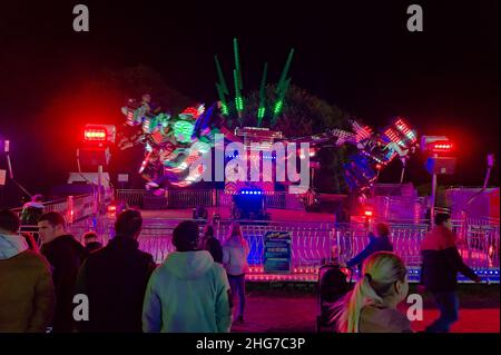 Les gens regardant un tour équitable la nuit pendant la foire annuelle de mai qui a eu lieu plus tard cette année-là en raison de covid 19 Banque D'Images