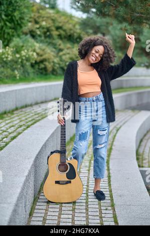 Femme touchant une guitare debout dans le parc pendant la journée Banque D'Images