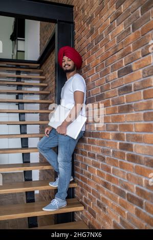 Jeune indien en turban rouge debout sur les escaliers Banque D'Images