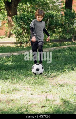 Enfant jouant au football dans la cour Banque D'Images