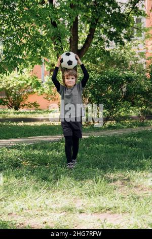 Enfant jouant au football dans la cour Banque D'Images