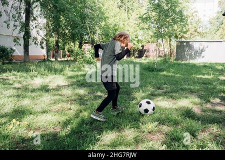 Enfant jouant au football dans la cour Banque D'Images