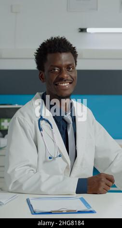 Un médecin portant un uniforme médical assis au bureau avec un ordinateur portable moderne, des dossiers de documents et du matériel de santé au bureau de la clinique médicale.Un appareil photo professionnel digne d'une médaille Banque D'Images