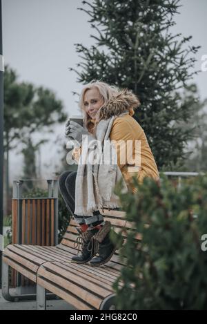 Une jolie femme âgée avec des cheveux blonds boit du café Banque D'Images