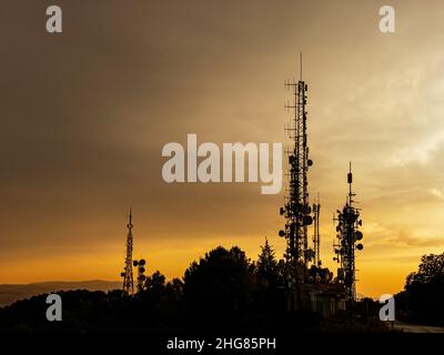 Antennes de télécommunication avec coucher de soleil sur fond. Banque D'Images