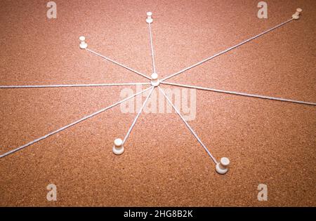 Un tableau de preuve en liège avec plusieurs cordes du point central allant vers les broches autour du tableau. Banque D'Images