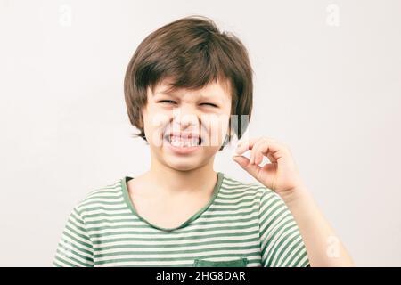 Kid n'est pas heureux de voir son bébé toth tomber.Un garçon mécontent tenant sa dent tombée à la main Banque D'Images