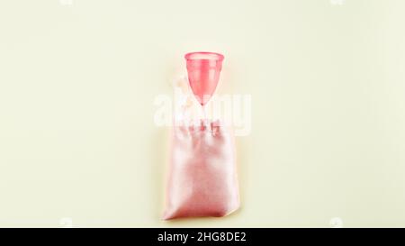 Gobelet menstruel en silicone rose et sac de rangement en tissu rose sur fond beige.Espace pour texte, vue de dessus.Femmes outil sanitaire pour confortable et Sutai Banque D'Images