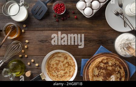 Recette pour faire des crêpes fines pour Shrovetide ou pour le petit déjeuner, vue de dessus sur la table en bois avec des ingrédients pour faire des crêpes russes, espace de copie Banque D'Images