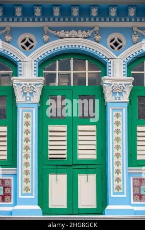 Vue rapprochée de face d'un atelier Peranakan d'avant-guerre à Singapour, présentant des fenêtres cintrées complexes, des volets en bois anciens et des carreaux. Banque D'Images