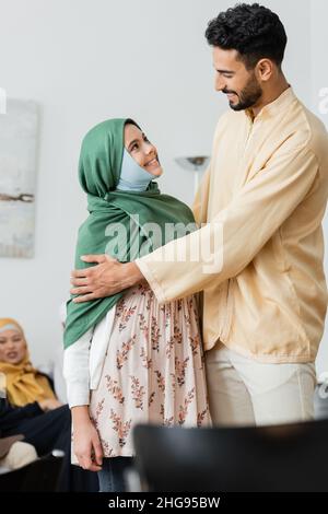 un homme arabe heureux embrassant la fille musulmane dans le hijab à la maison Banque D'Images