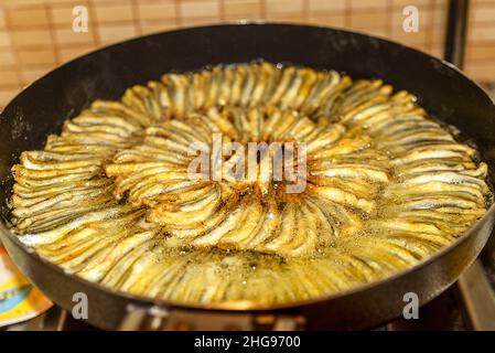 Les poissons anchois soigneusement alignés dans une grande casserole sont frits à la maison Banque D'Images