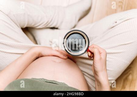 Une femme enceinte tient une tasse de café dans ses mains.Innocuité de la caféine, mythes sur le café pendant la grossesse concept .Photo de haute qualité Banque D'Images