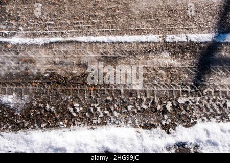 traces de pneu sur la neige fondante sur l'asphalte. Banque D'Images