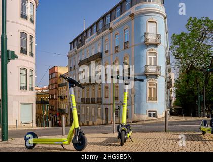 Lisbonne, Portugal - 10 juillet 2021: Deux scooters électriques avec LOGO DE LIEN sur le trottoir, pas de personnes, pas de voitures.Été, lumière du jour, ciel bleu, maisons anciennes Banque D'Images