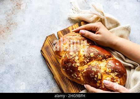 Femme plaçant un pain de Pâques tsoureki traditionnel avec des amandes sur une planche à découper Banque D'Images