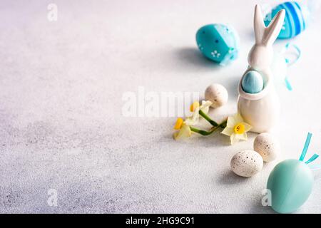 Peint les décorations d'oeuf de Pâques et de lapin de Pâques sur une table avec des fleurs de narcisse Banque D'Images