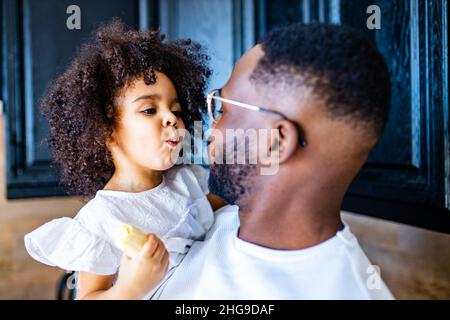 Portrait d'un homme embrassant une petite fille à la maison et mangeant une banane Banque D'Images