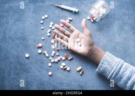 addiction de drogue concept avec la main tenant des pilules et la seringue sur le sol Banque D'Images