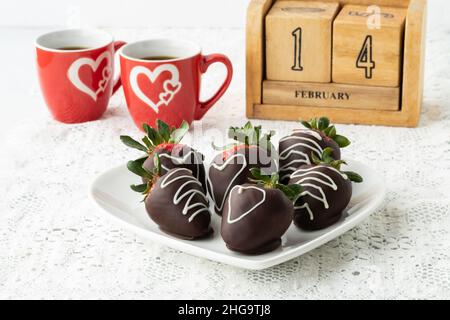 Célébrez la Saint-Valentin avec des fraises enrobées de chocolat et du café. Banque D'Images