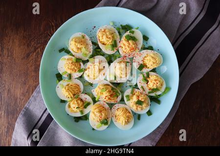 Oeufs découpés saupoudés de paprika et d'oignon vert haché sur une assiette verte sur une table de courge .Vue de dessus Banque D'Images