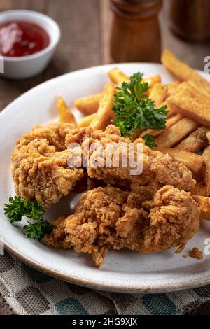 Filets de poulet frits croustillants et frites garnies de persil sur une assiette Banque D'Images