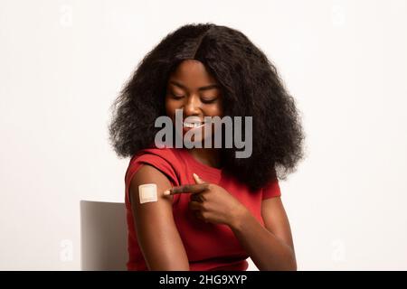 Portrait d'une femme afro-américaine vaccinée pointant vers le bandage adhésif sur le bras Banque D'Images