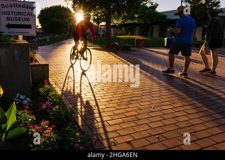 Un cycliste de sexe masculin se dirigeant à vélo vers le centre civique de Scottsdale dans la vieille ville de Scottsdale, Arizona, États-Unis. Banque D'Images