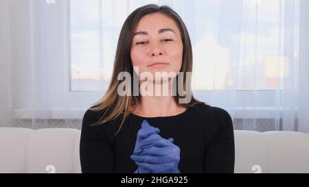 Femme en gants de protection bleus utilisant du gel désinfectant pour les mains pour prévenir les épidémies virales ou les agents antibactériens. Banque D'Images